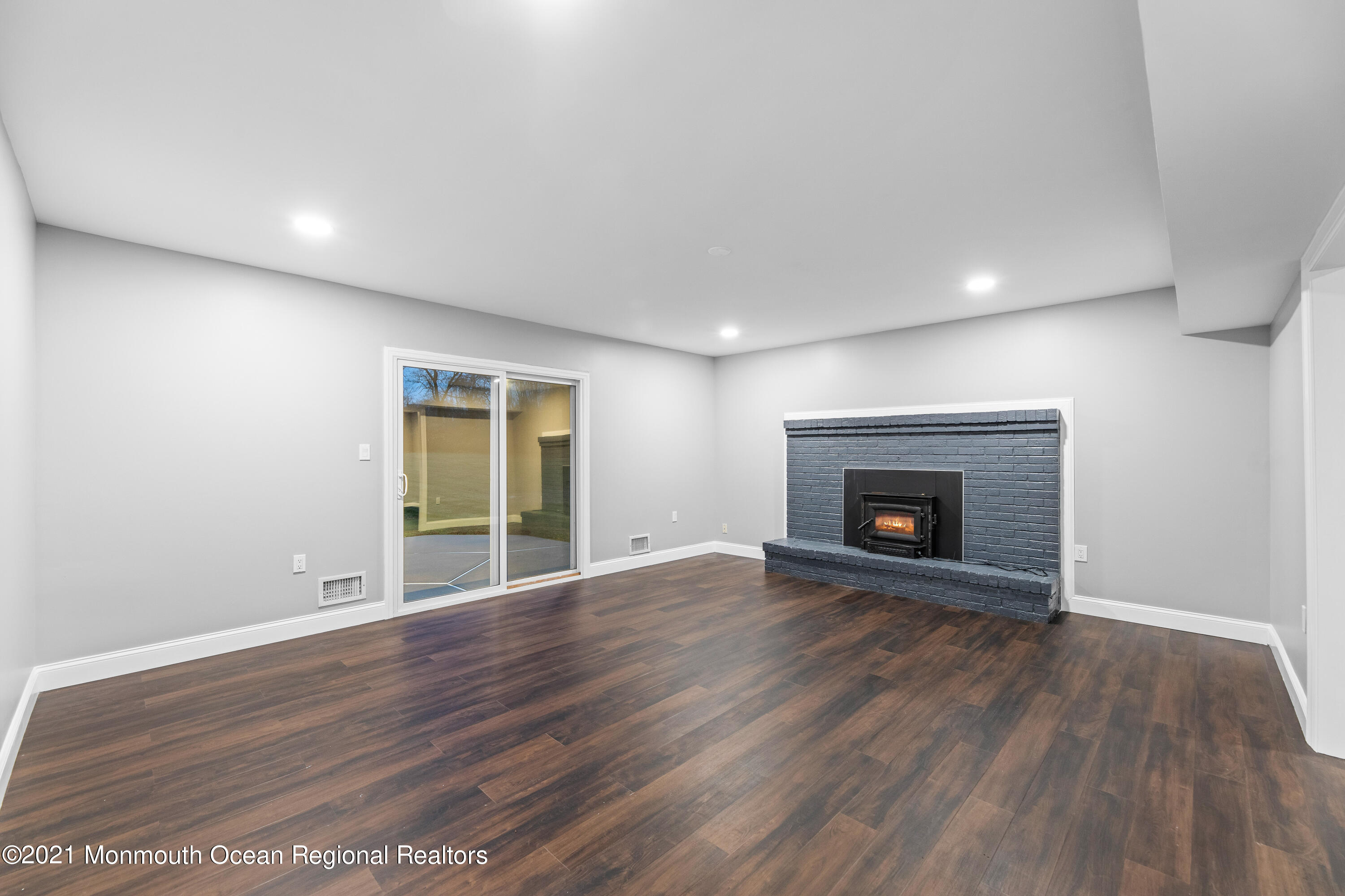 26 Squan Road Millstone Township, NJ 08510 - Photo 10 of 24 an empty room with wooden floor and a fireplace