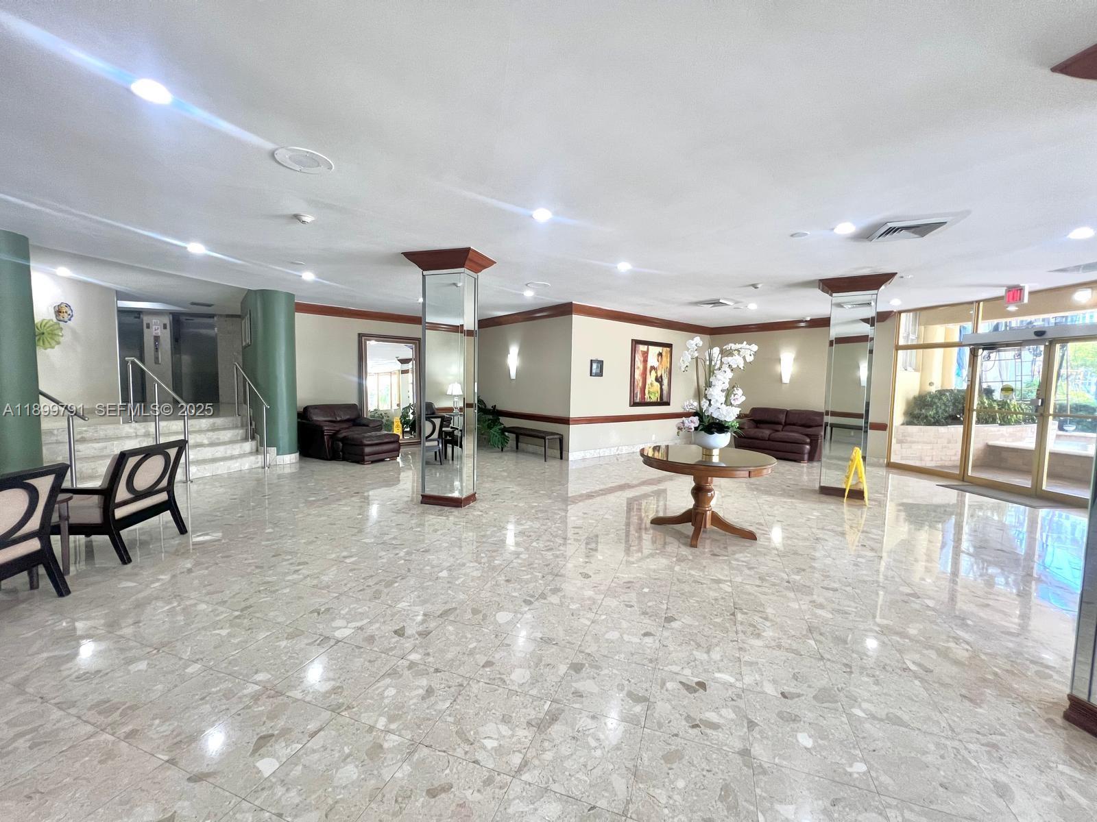 100 Golden Isles Drive, Unit 406 Hallandale Beach, FL 33009 - Photo 24 of 31 a living room with furniture and a dining table with kitchen view