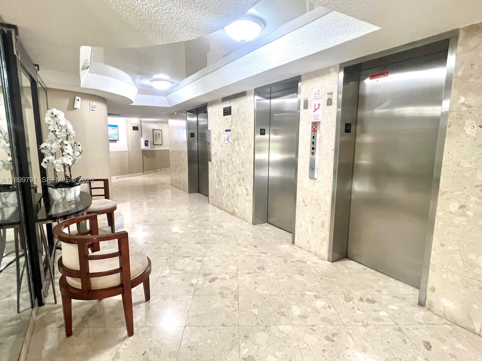 100 Golden Isles Drive, Unit 406 Hallandale Beach, FL 33009 - Photo 25 of 31 a bathroom with a glass shower door and chair