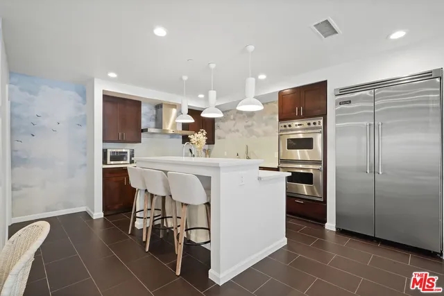 a kitchen with stainless steel appliances kitchen island granite countertop a refrigerator and a sink