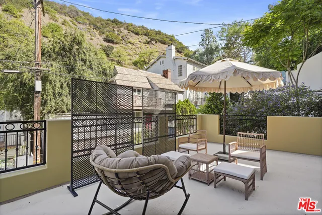 a view of a patio with couches table and chairs under an umbrella