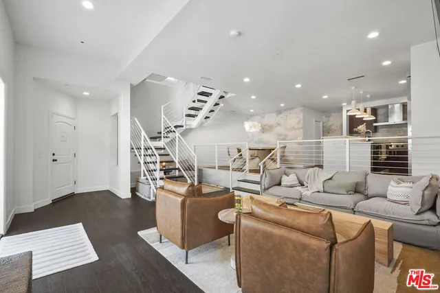 a living room with furniture kitchen view and a chandelier