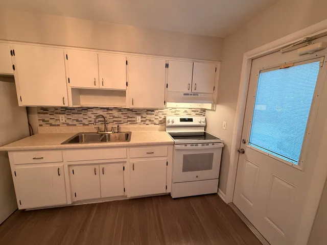 a kitchen with stainless steel appliances white cabinets and wooden floors