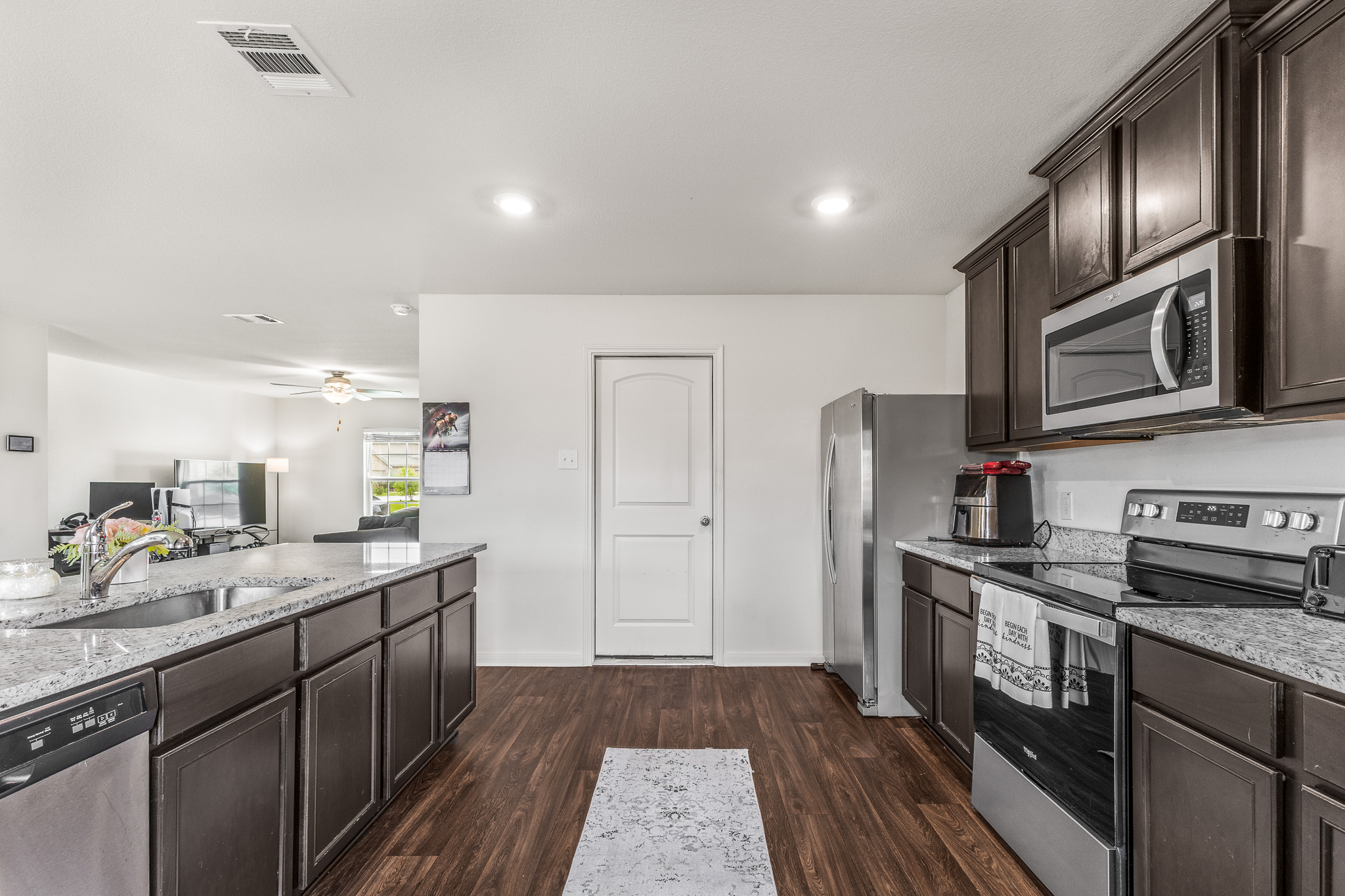 304 Hyacinth Way, Unit #7K Jarrell, TX 76537 - Photo 9 of 26 A contemporary kitchen features dark cabinetry, light granite countertops, and stainless steel appliances.