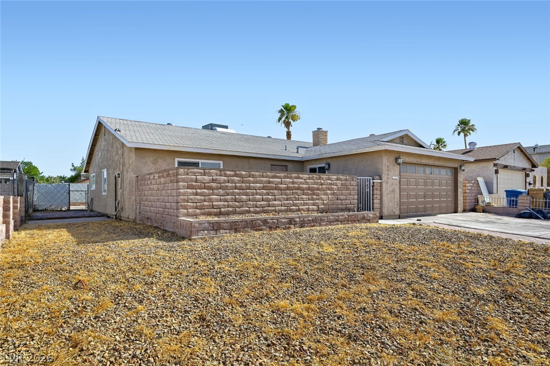 6321 Portola Road Las Vegas, NV 89108 - Photo 3 of 29 A modest stucco exterior, with a two-car garage, presents a simple and functional residence.