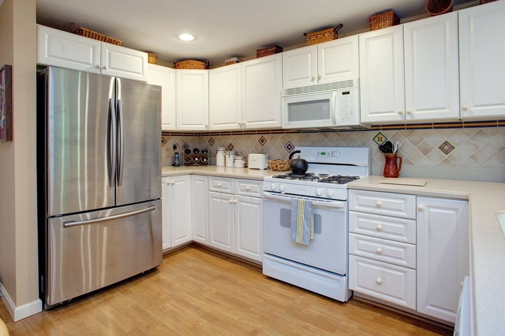 10 Kettle Lane, Unit 10 Mashpee, MA 02649 - Photo 9 of 31 a kitchen with cabinets stainless steel appliances and wooden floor