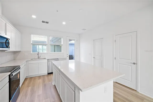 a kitchen with white cabinets a sink dishwasher and a stove with wooden floor