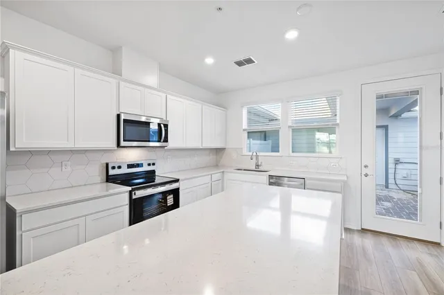 a kitchen with granite countertop a stove a sink and a refrigerator
