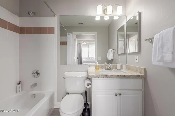 a bathroom with a granite countertop sink a toilet a mirror a vanity and bathtub