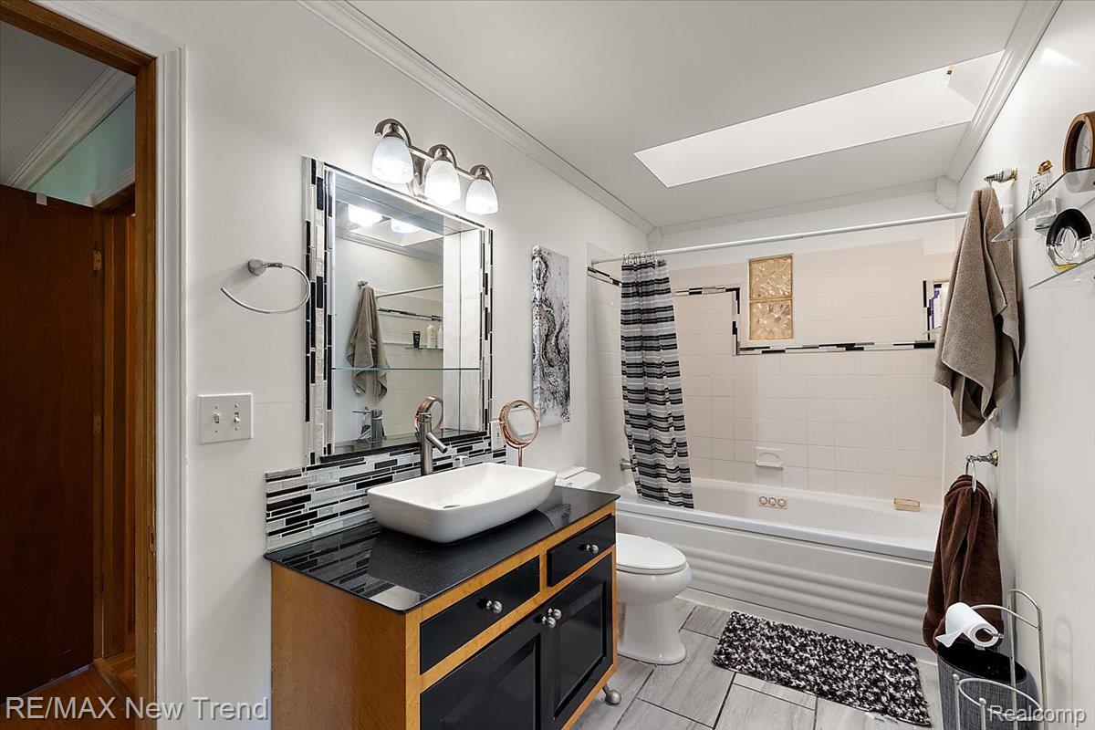 1450 Lenox Road Bloomfield Hills, MI 48304 - Photo 56 of 79 White vanity with vessel sink, black countertop, mosaic tile backsplash, and mounted mirror