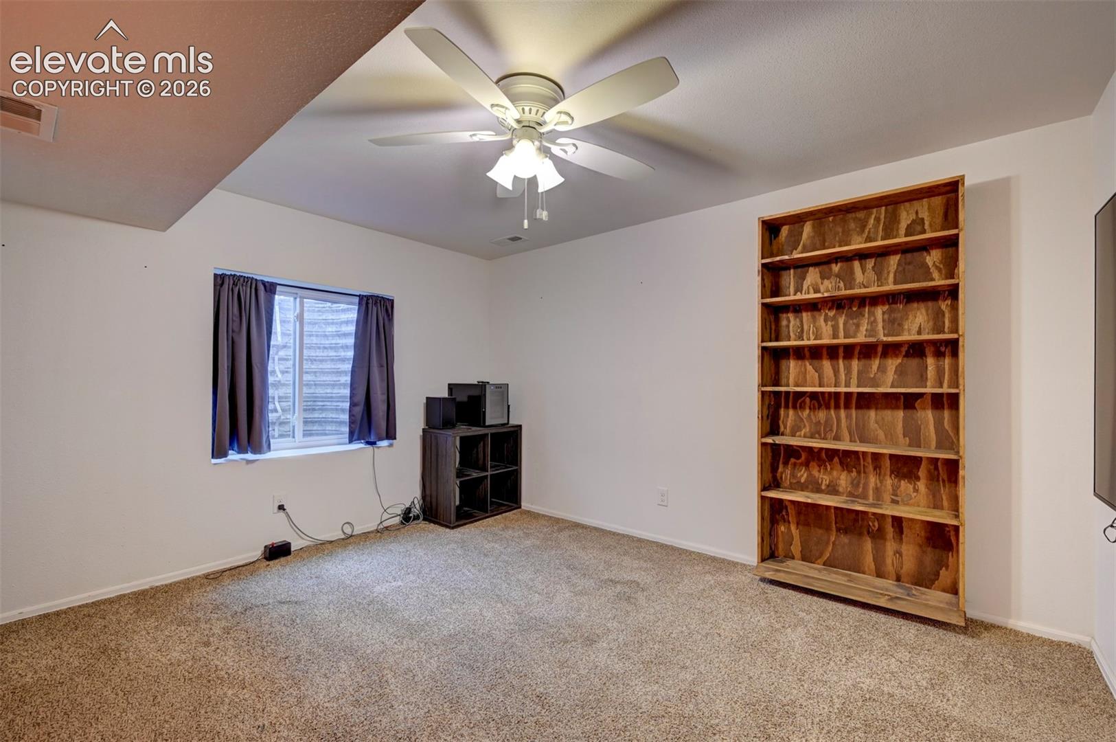 8170 Valli Farm Road Fountain, CO 80817 - Photo 31 of 50 Built-in wood shelving, textured carpeting, and a ceiling fan with integrated lighting
