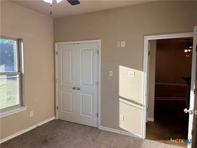 an empty room with wooden floor and a chandelier fan