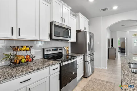 a kitchen with stainless steel appliances granite countertop a refrigerator and a stove top oven