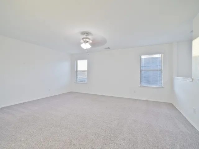 an empty room with windows and chandelier fan