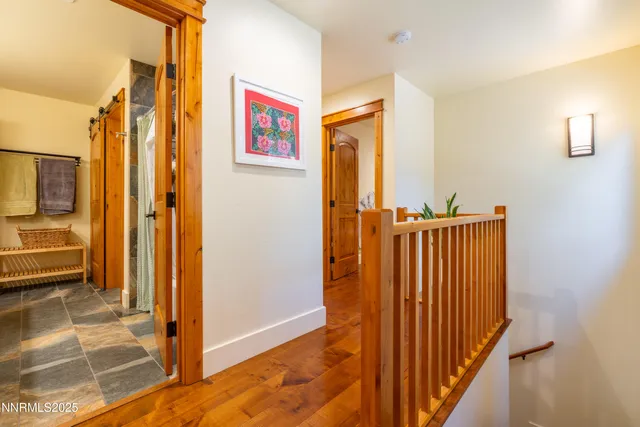 a view of a hallway with wooden floor and a bathroom