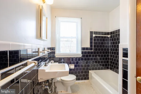 a bathroom with a sink a toilet a window and a bathtub