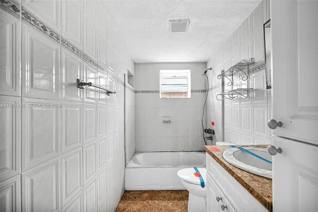 a bathroom with a granite countertop sink a toilet and mirror