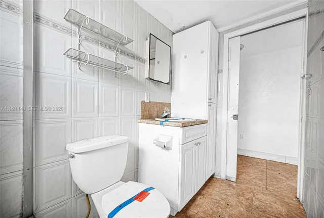 a kitchen that has a lot of white cabinets and a wooden floor