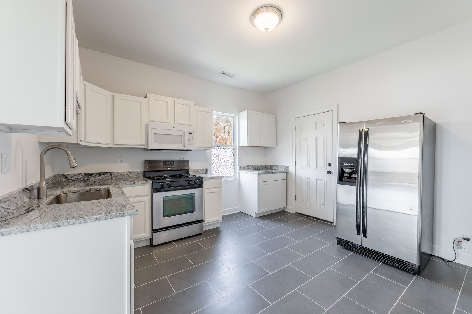 4140 West Maypole Avenue, Unit 2 Chicago, IL 60624 - Photo 12 of 24 a kitchen with granite countertop a refrigerator sink and cabinets