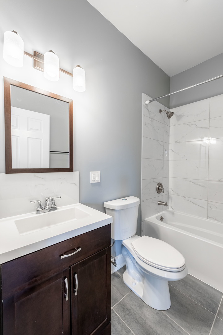 4140 West Maypole Avenue, Unit 2 Chicago, IL 60624 - Photo 14 of 24 a bathroom with a toilet a sink a mirror a bathtub and shower