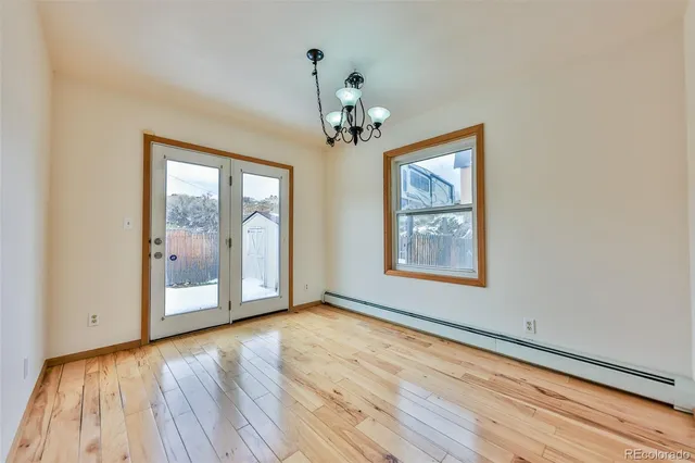 a view of an empty room with window and wooden floor