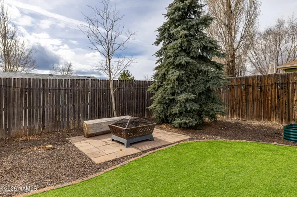 a view of backyard with wooden fence and a large tree