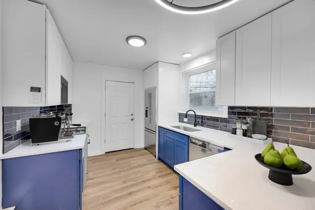 a kitchen with stainless steel appliances a sink a counter top space cabinets and wooden floor