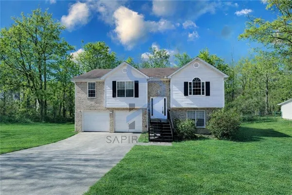 a front view of a house with a yard and trees