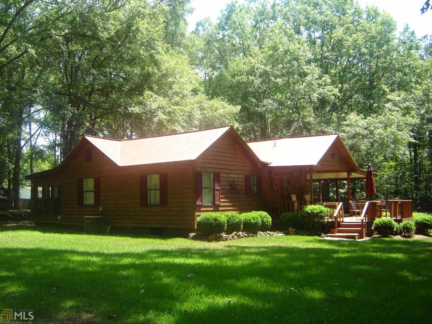 a backyard of a house with table and chairs plants and large tree