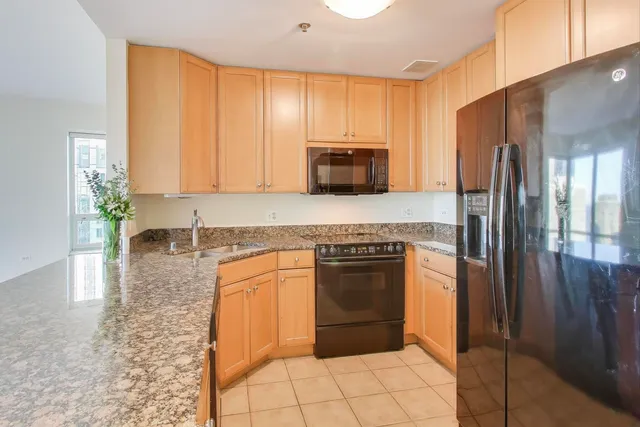 a kitchen with granite countertop a refrigerator and a stove top oven