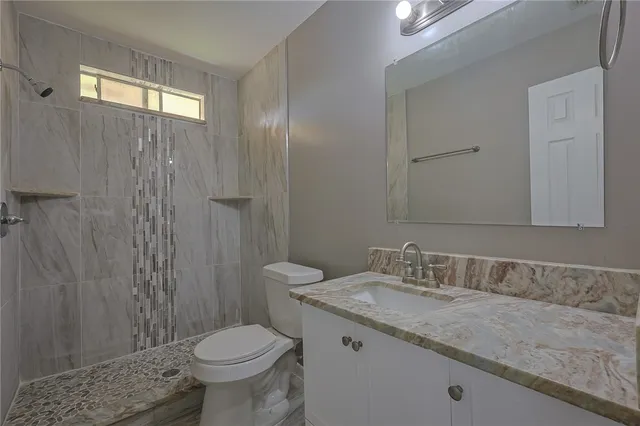a bathroom with a granite countertop toilet sink and mirror