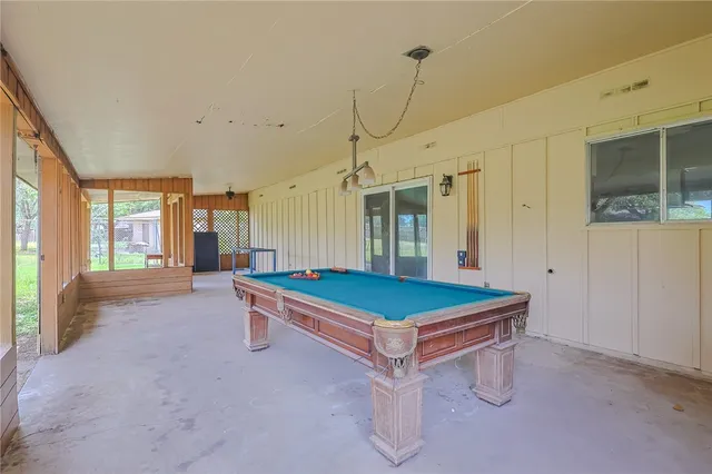 a room with pool table and windows