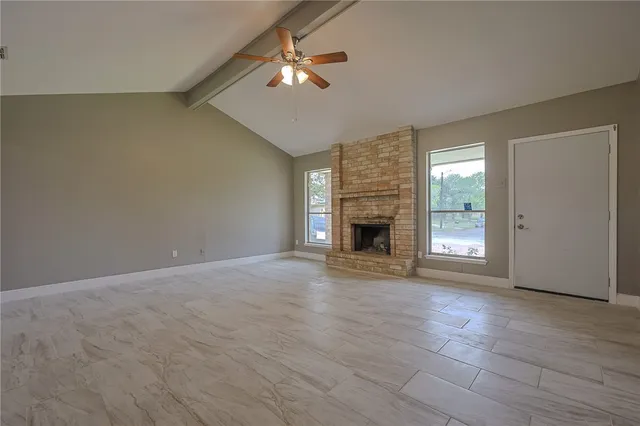 an empty room with windows and fireplace