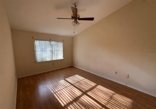 a view of an empty room with a window and wooden floor