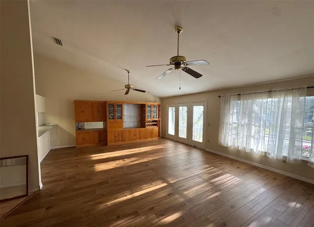 a view of an empty room with window and wooden floor