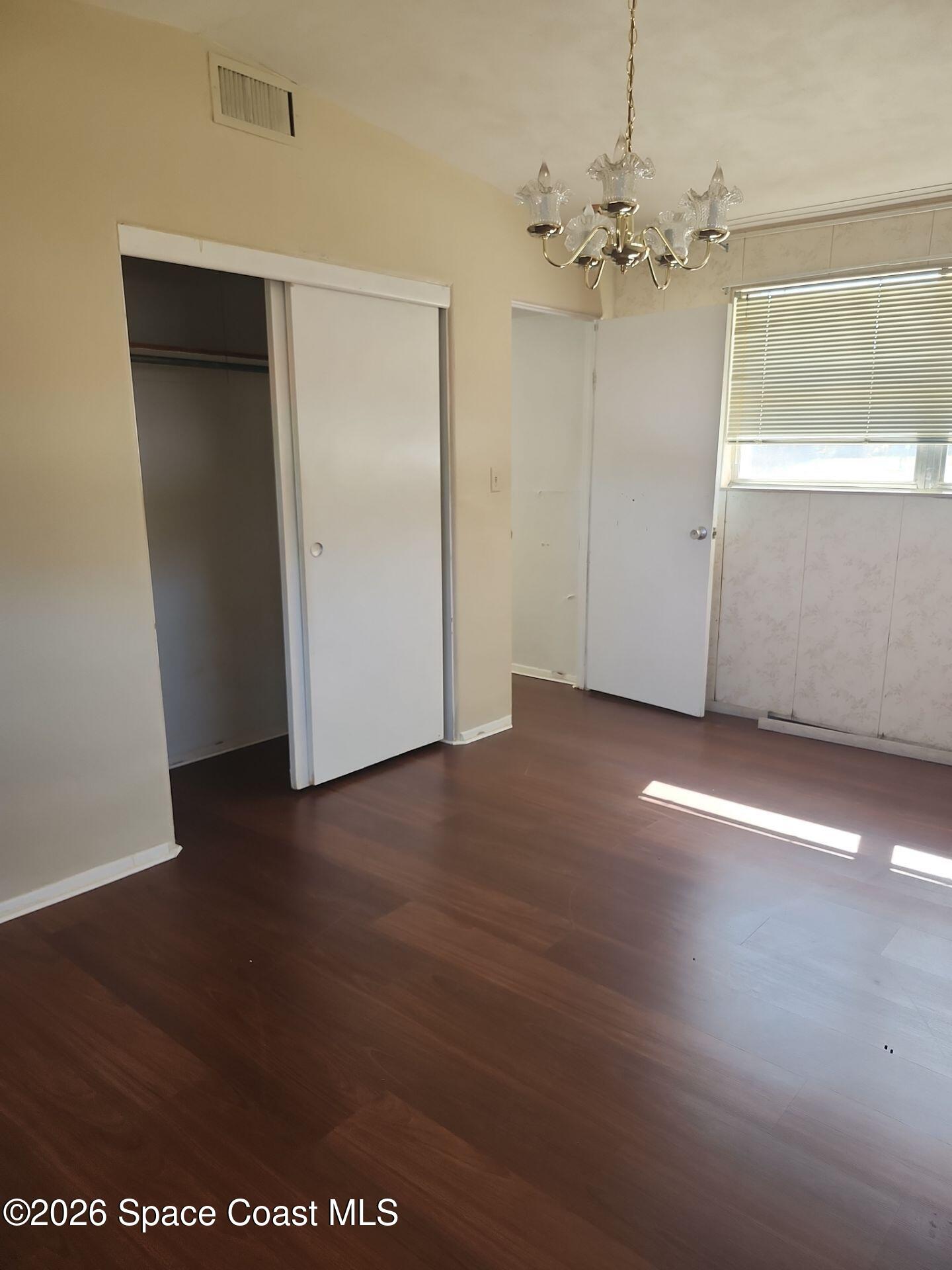 180 Church Road Merritt Island, FL 32953 - Photo 12 of 14 an empty room with wooden floor chandelier and windows