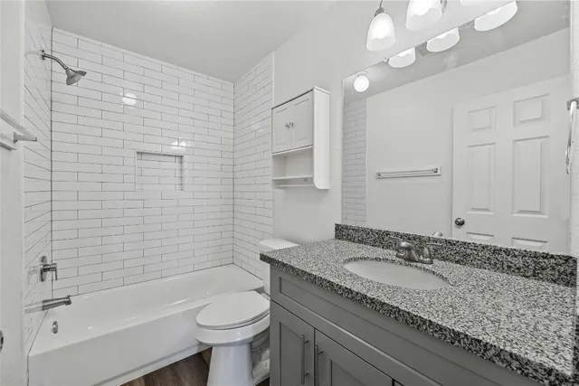 a bathroom with a granite countertop sink toilet and shower
