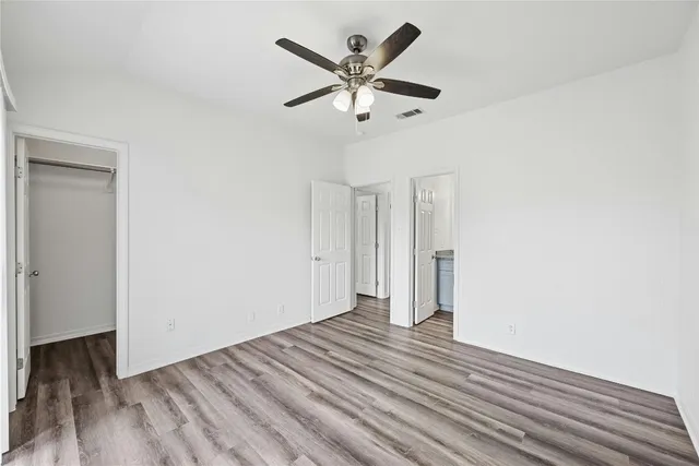 an empty room with wooden floor and ceiling fan