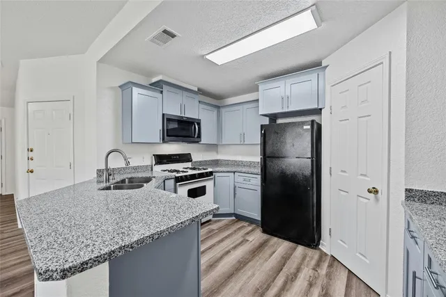 a kitchen with granite countertop a refrigerator a stove a sink a microwave and island