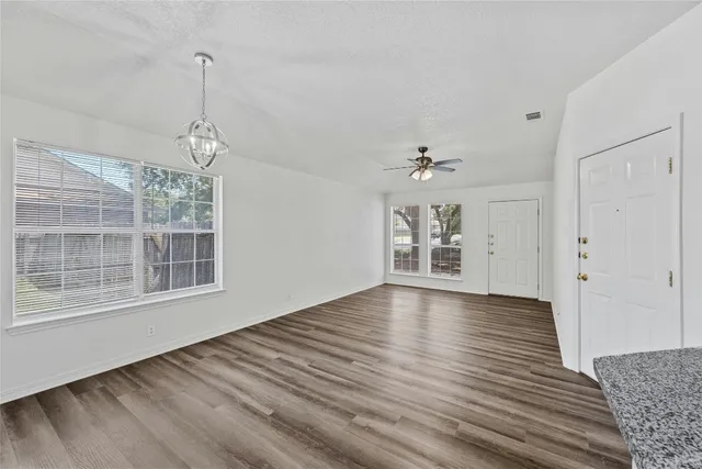 a view of an empty room with a window and wooden floor