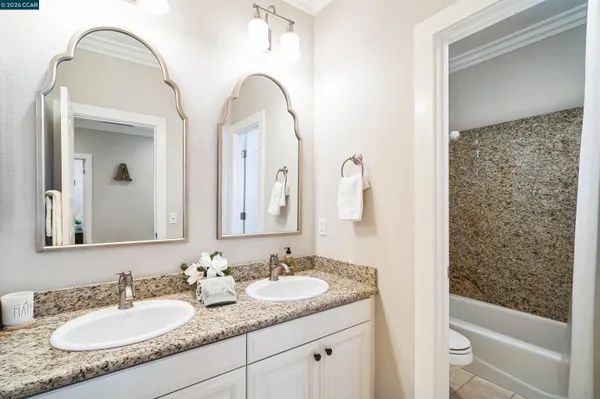 a bathroom with a granite countertop sink a toilet and a mirror