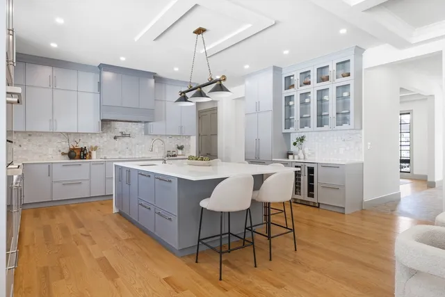 a large kitchen with cabinets a sink a center island and stainless steel appliances