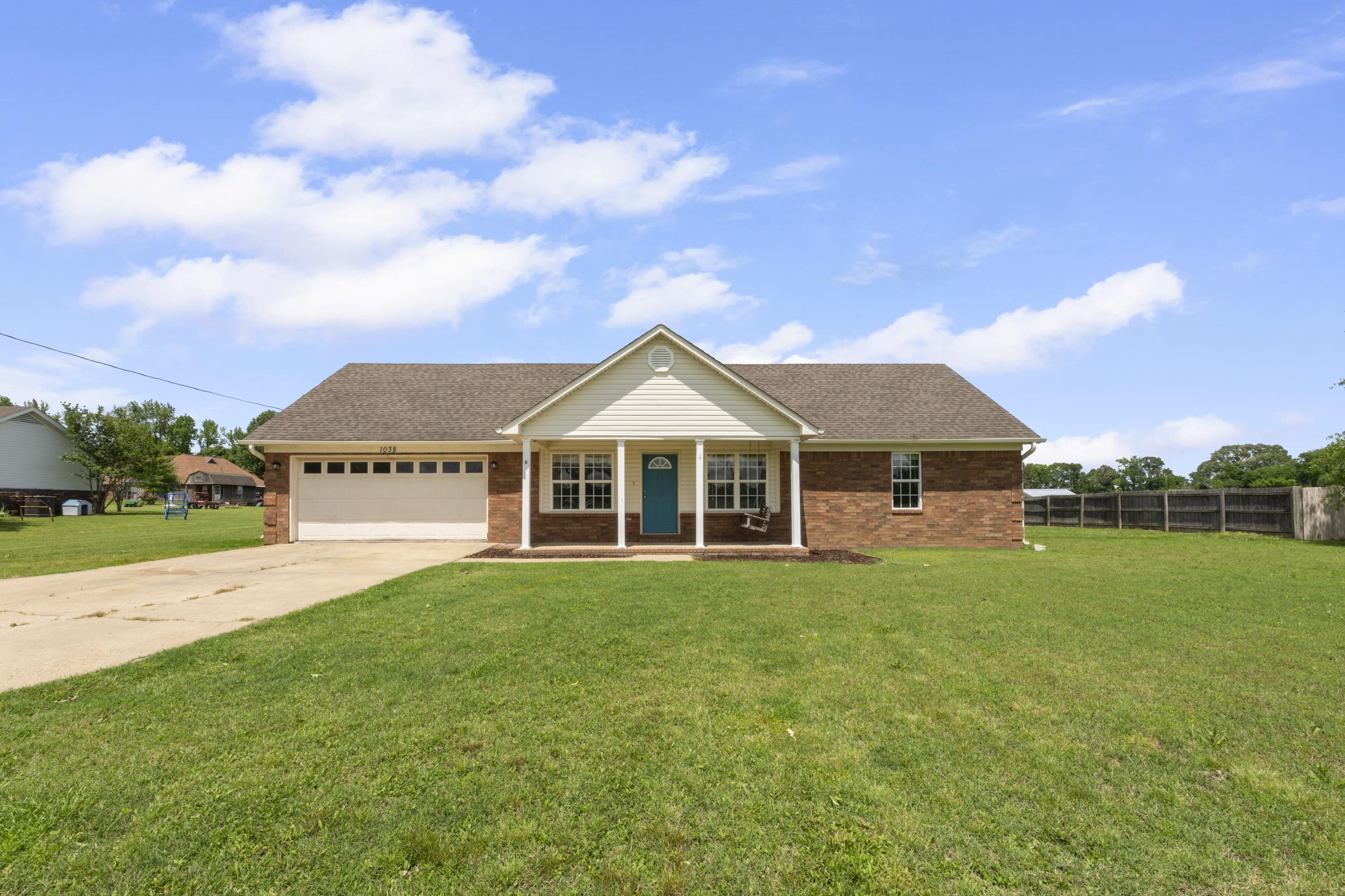 1038 Jamestown Road Burlison, TN 38015 - Photo 1 of 24 View of front of property featuring driveway, fence, a garage, a front yard, and a porch