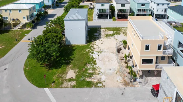 a view of a white house with a big yard and potted plants and large trees