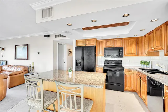 a kitchen with stainless steel appliances granite countertop a stove top oven a sink dishwasher a dining table and chairs with wooden floor