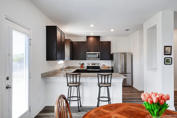 a kitchen with stainless steel appliances a refrigerator a stove a sink a dining table and chairs