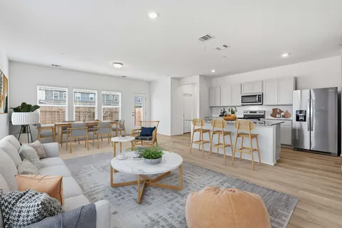 a living room with furniture and a dining table with kitchen view
