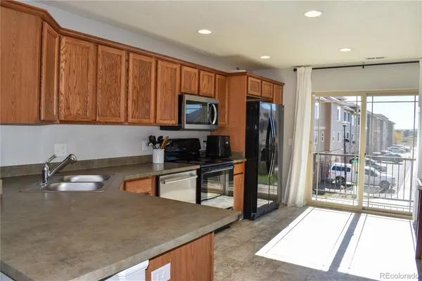 a kitchen with stainless steel appliances granite countertop a refrigerator a stove and a sink with wooden cabinets
