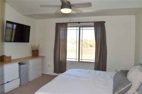 a bedroom with a bed and a flat tv screen on dresser