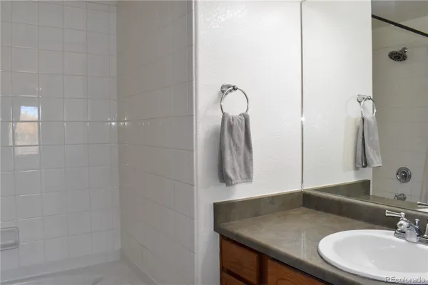 a bathroom with a granite countertop sink a mirror and shower
